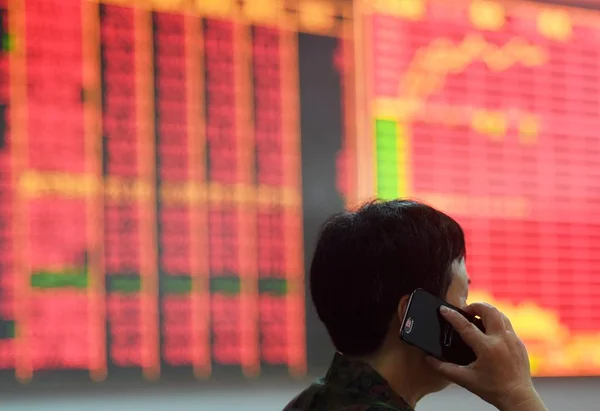 中国の投資協議彼のスマート フォンで過去の株価指数や株式 赤の価格上昇のため と緑の価格の落下のための価格を表示する画面について説明 日中国東部の浙江省杭州市の証券の家で — ストック写真