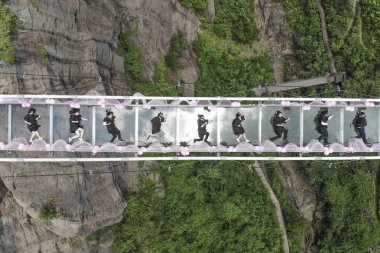 Graduates from Changsha city pose for creative graduation photos on a glass-bottomed bridge at the Shiniuzhai National Geological Park or Pingjiang Shiniuzhai Geopark in Pingjiang couty, Yueyang city, central China's Hunan province, 27 June 2018 clipart
