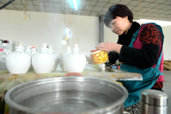 中国人労働者は中国の甘粛州北西部の Wuwei 市の工場で中国の精神を含むために使用される西洋の霞の磁器の瓶を生産します 月2018 — ストック写真