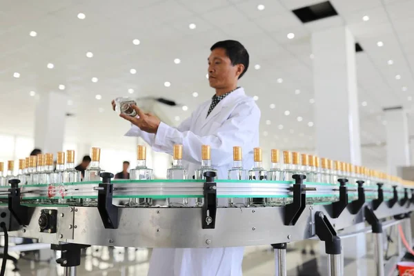 中国の労働者は白酒酒の中国のブランドである Moutai から派生した Daqu Bijie のボトルを生産しており それは Bijie 市の生産工場での組立ラインの貴州州西南部 4月10日2018 — ストック写真