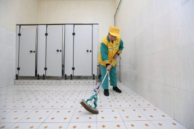 A Chinese worker cleans a public toilet in Xi'an city, northwest China's Shaanxi province, 13 January 2017 clipart