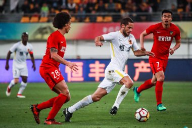 Spanish soccer player Mario Suarez, right, of Guizhou Hengfeng kicks the ball to make a pass against Belgian football player Axel Witsel of Tianjin Quanjian in their fifth round match during the 2018 Chinese Football Association Super League (CSL) in