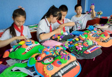 Primary school students make traditional auspicious beast masks under the guidance of their teachers in Hohhot city, north China's Inner Mongolia Autonomous Region, 27 June 2018 clipart