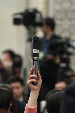 A reporter holds panoramic shooting equipment during a press conference before the opening meeting for the first session of the 13th National Committee of the Chinese People's Political Consultative Conference (CPPCC) in Beijing, China, 2 March 2018. clipart