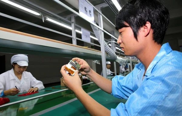 中国の労働者は 中国南西部の四川省の華寧市の工場で携帯電話を組み立てます 2014年6月20日 — ストック写真