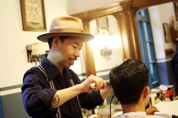 男性のヴィンテージスタイルのヘアカットだけに焦点を当てた理髪店と呼ばれる上海を拠点とする理髪店のオーナーは 中国の上海で顧客のためにレトロなヘアスタイルを手配します 2018年4月5日 — ストック写真