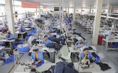 Female Chinese workers sew clothes to be exported to Southeast Asian countries at a garment factory in Huaibei city, east China's Anhui province, 19 January 2016 clipart