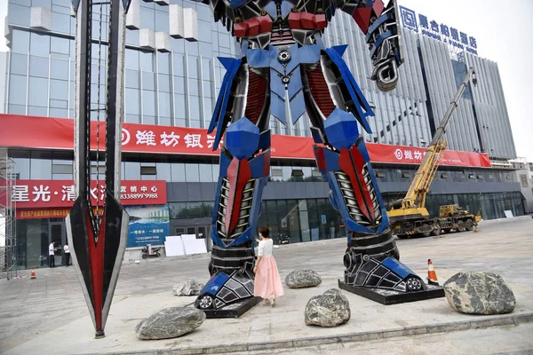 2018年6月25日 在中国东部山东省聊城 一位中国妇女看着用汽车废料制成的Optimus Prime的复制品 — 图库照片