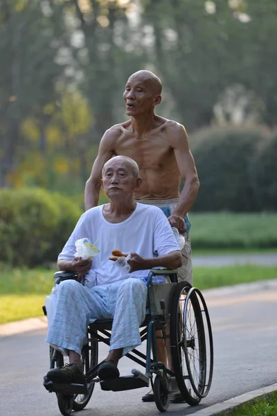 2013年8月9日 中国上海一家公园 一位64岁的无上身老人推着轮椅 与86岁高龄的父亲一起散步 — 图库照片