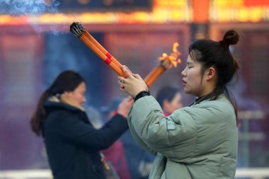 A Chinese worshipper burns joss sticks (incenses) to pray for good fortune and blessing at a temple in Huai'an city, east China's Jiangsu province, 24 January 2018. clipart