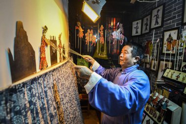 60-year-old Chinese folk artist Chen Shouke performs shadow play or shadow puppetry, also known as shadow puppet, in Tai'erzhuang district, Zaozhuang city, east China's Shandong province, 1 March 2018 clipart
