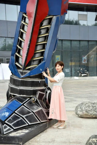 2018年6月25日 在中国东部山东省聊城 一名中国妇女摆出一副用汽车废料制作的Optimus Prime复制品的照片 — 图库照片