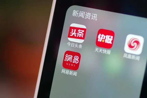 中国の携帯電話ユーザーは 左上から Toutiao 天安クアイバオ フェニックスニュース ネットイースニュースのモバイルアプリのアイコンを見て 中国東部の山東省 Nan市で彼のスマートフォンで 2018年4月9日 — ストック写真