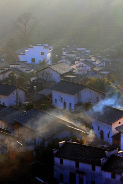 Winter scenery of ancient houses with Mau Tou Wall (Horse Head Wall) with smoke from kitchen chimneys in Wuyuan county, Shangrao city, east China's Jiangxi province, 10 January 2018 clipart