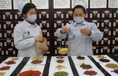 Chinese pharmaceutists dispense traditional Chinese medicine at a TCM pharmacy in Handan city, north China's Hebei province, 21 December 2017 clipart