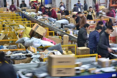 Chinese workers sort out piles of parcels, most of which are from Singles Day online shopping, at a distribution center of YTO Express in Neijiang city, southwest China's Sichuan province, 15 November 2017 clipart