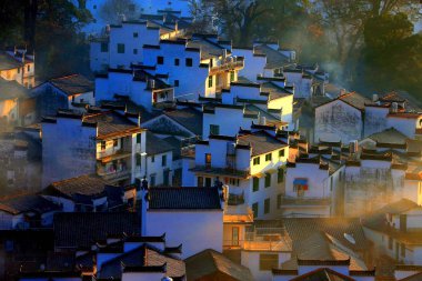 Winter scenery of ancient houses with Mau Tou Wall (Horse Head Wall) with smoke from kitchen chimneys in Wuyuan county, Shangrao city, east China's Jiangxi province, 10 January 2018 clipart