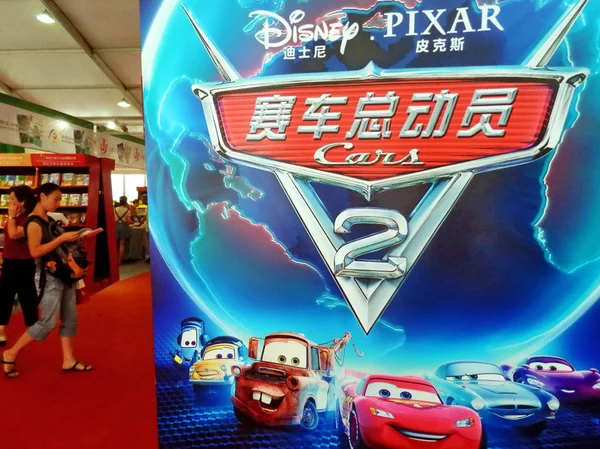 2011年8月19日 上海で開かれたブックフェアで ディズニー エンタープライズ社のピクサー映画 Cars のポスターを通り過ぎる人々 — ストック写真