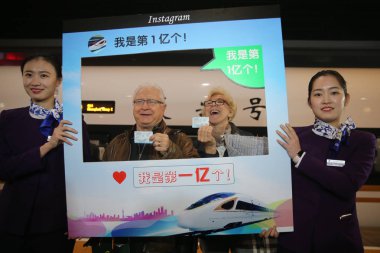 79-year-old American businessman Charles Bingham, who is the city's 100 millionth outbound train passenger this year, poses for photos with his wife after he bought train tickets at the Hongqiao Railway Station in Shanghai, China, 4 December 2017 clipart