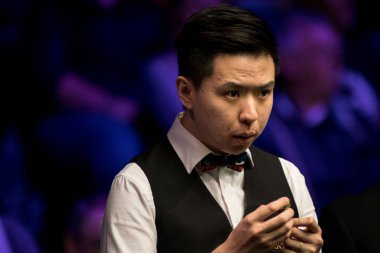 Xiao Guodong of China chalks his cue as he considers a shot to Martin Gould of England in their fourth round match during the 2017 Betway UK Championship snooker tournament in York, UK, 7 December 2017
