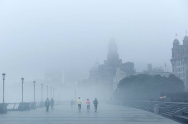 Pedestrians walk on the promenade on the Bund along the Huangpu River in heavy fog in Puxi, Shanghai, China, 16 January 2018.   clipart