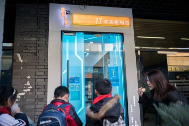 Customers scan a QR code via mobile payment service Alipay of Alibaba Group on their smartphones to enter an abandoned self-service banking area transformed into an unmanned convenience store in Hangzhou city, east China's Zhejiang province, 21 Decem clipart