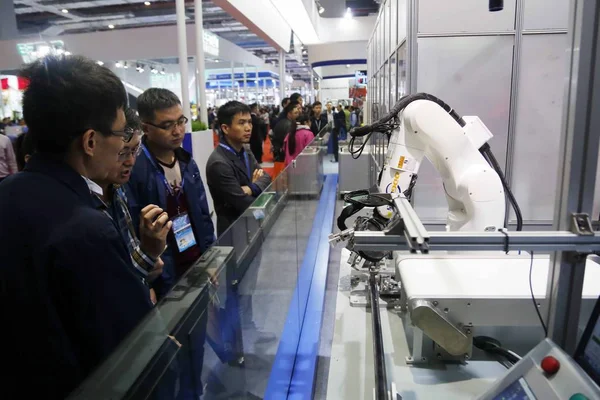 在2017年11月7日于中国上海举行的第19届中国国际工业博览会上 游客们在奥奇展台观看机器人手臂 — 图库照片