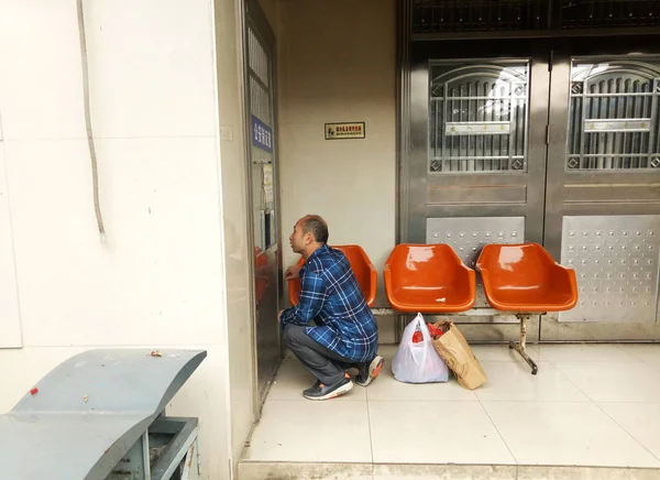2017年4月17日 在中国中部湖南省株洲市株洲火车站 一名中国男子蹲下跪在一个低矮的小服务窗口前 获得临时身份证 — 图库照片