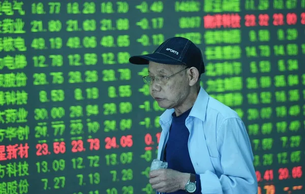 2017年4月24日 中国东部浙江省杭州市一家股票经纪公司 一位关心此事的中国投资者走过一个屏幕 显示股价 价格上涨为红色 价格下跌为绿色 — 图库照片