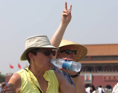 Foreign tourists shielded with hats from the scorching sun take photos as they visit the Tian'anmen Square in Beijing, China, 20 May 2017 clipart