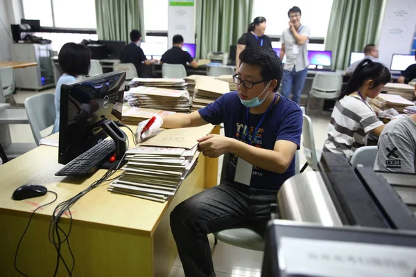 2017年6月12日 中国南部海南省海口市で行われた2017年国家大学入試の解答用紙を中国人教師がスキャンする — ストック写真