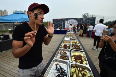 A foreigner tries out a fried spider during a challenge to eat weird Chinese cuisines in Beijing, China, 13 July 2017 clipart