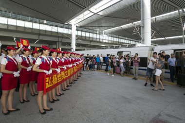 Passengers look at attendants posing in front of the new bullet train on the BaojiCLanzhou High-Speed Railway at the Xi'an North Railway Station in Xi'an city, northwest China's Shaanxi province, 9 July 2017  clipart