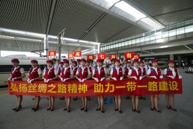 Chinese artists dressed in traditional costumes of different ethnic groups and an attendant pose in front of the new bullet train on the BaojiCLanzhou High-Speed Railway at the Xi'an North Railway Station in Xi'an city clipart