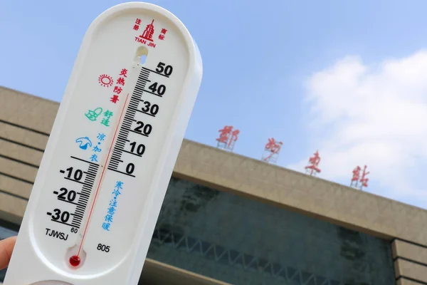 2017年7月13日 在中国中部河南省郑州市郑州东站前 一位当地居民展示了一个温度计 显示高温天温度达到36摄氏度 — 图库照片