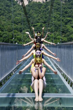 Female graduates dressed in bikinis pose for graduation photos on the glass bridge at the Tianlongchi scenic area in Pingdingshan city, central China's Henan province, 18 June 2017 clipart