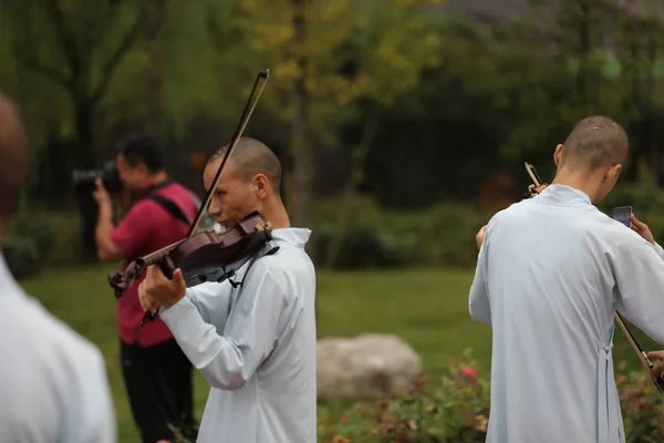 中国首家在湖北天台寺的古典佛教音乐专业学院的和尚和尼姑在黄龙音乐节和黄龙洞穴哈利路亚音乐厅的国际合唱周期间拉小提琴 — 图库照片