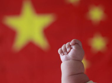 A newborn baby is pictured in front of the national flag of the People's Republic of China in Anyang city, central China's Henan province, 29 September 2015 clipart