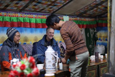 A young Tibetan man makes tea for customers and travelers in his tent tea house at the foot of Mount Everest, or Qomolangma, in Tingri county, Shigatse, southwest China's Tibet Autonomous Region, 20 August 2017 clipart