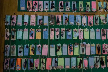 Aerial view of parents of freshmen students who escorted their children for enrollment on their first day of study resting on mats laid out on the floor at a gymnasium of South-central University For Nationalities in Wuhan city, central China's Hubei clipart