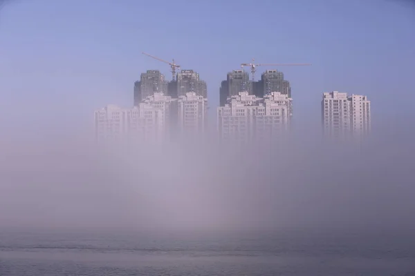 高層ビルや高層ビルは 中国の湖北省襄市の Hanjiang 川に沿って蜃気楼が現れるように漠然と見られている 月2017 — ストック写真