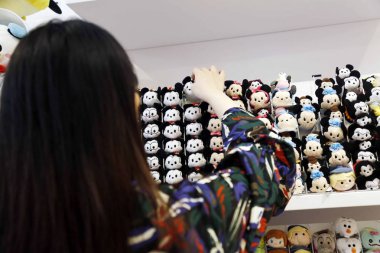 A customer looks at Mickey Mouse dolls and Minnie Mouse dolls displayed at the China's second Disney store in HKRI Taikoo Hui, Shanghai, China, 2 September 2017. clipart