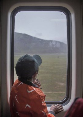 A Tibetan boy looks out of the window on a train running from Xining to Lhasa on the Qingzang (Qinghai-Tibet) Railway in southwest China's Tibet Autonomous Region, 9 August 2017 clipart