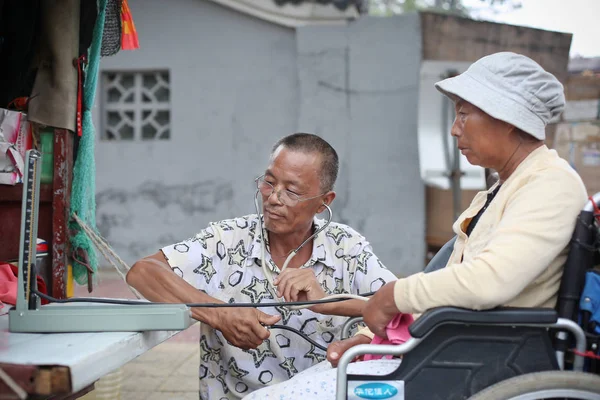 中国の Jingxin 彼らの全国ツアーで3輪車から彼が回した の隣に彼の麻痺した妻のための血圧を測定し 中央中国の河南省 鄭州市では 月2017 — ストック写真