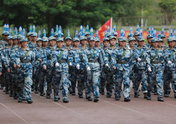 新入生として彼らは軍事訓練で屋外陸上競技場南寧市の大学のキャンパスに中国南部の広西チワン族自治区南寧市職業技術の 2017 頭にボトルのバランスをとる — ストック写真