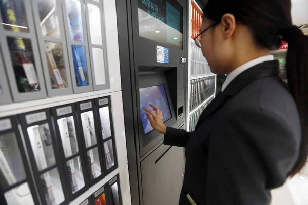 市民は アリババの Ant Yangpu 図書館 Jiatu ソフトウェア株式会社のジーマクレジットで運営されている共有本棚の前で無料で本を借りるためにマシンを使用しています中国 Yangpu 月2017 — ストック写真