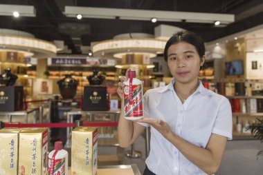 An employee shows a bottle of Kweichow Moutai liquor at a store in Renhuai city, southwest China's Guizhou province, 16 September 2017 clipart