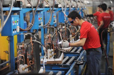 A Chinese worker welds parts for air-conditioners on the assembly line at a plant of TCL in Wuhan city, central China's Hubei province, 26 July 2017 clipart