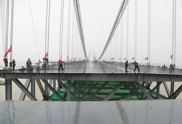 中国の労働者は 杭州ルイリ高速道路のパスに位置する第2東通湖橋を接続するためにクレーンを持ち上げるように 中国中央省雄陽市の東江湖の上のチェンリンジで 2017年8月15日 — ストック写真