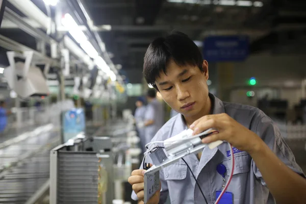 中国の労働者は 中国東部の山東省青島市の工場で組み立てライン上のエアコンのコンポーネントをチェックします 2017年7月24日 — ストック写真